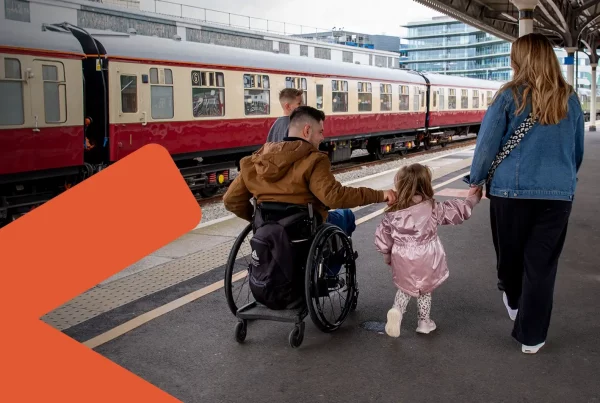 male wheelchair user with his family on train station platform with train