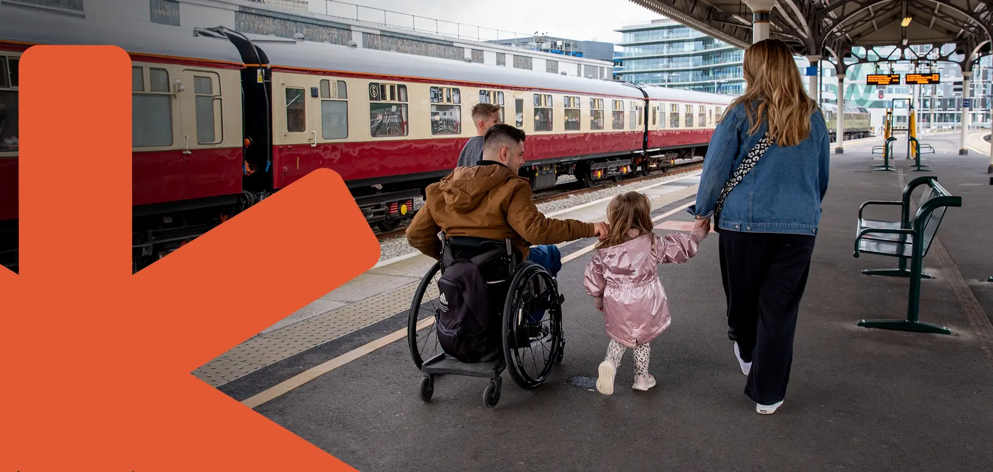 male wheelchair user with his family on train station platform with train